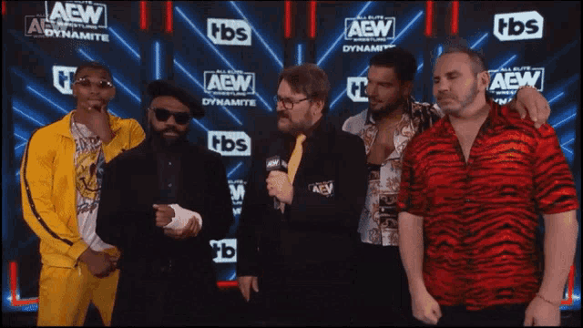 a group of men stand in front of a wall that says aew dynamite