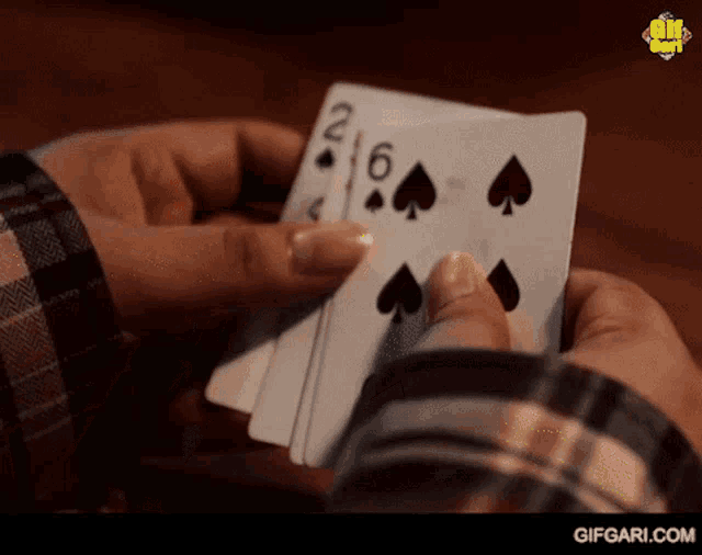 a person is holding a stack of playing cards in their hands including a pair of spades .