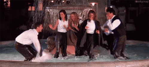 a group of people are standing in a fountain covered in water