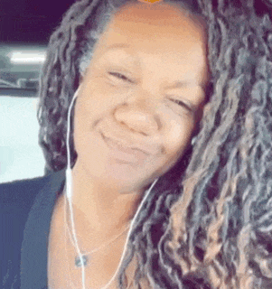 a woman with dreadlocks and headphones is smiling for the camera .
