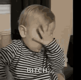 a baby is covering his face with his hand .