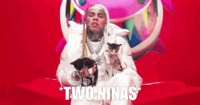 a man in a white jacket is holding two kittens in front of a pink background that says twoninas on it