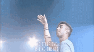 a man is raising his hand in the air with the words `` no other one is like our god '' behind him .