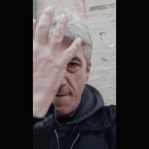 a man in a black jacket is covering his eyes with his hand
