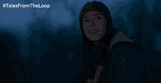 a woman wearing a knitted hat is smiling in the dark with #talesfromtheloop above her