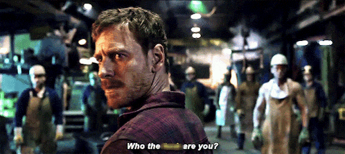 a man in a plaid shirt stands in front of a group of men and says who the are you