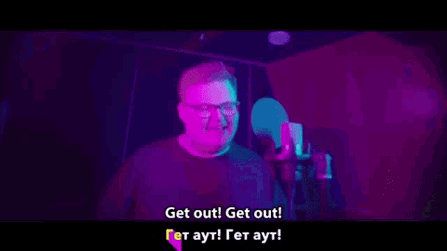 a man wearing glasses is singing into a microphone in front of a colorful background .
