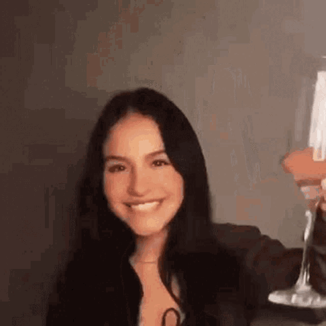 a woman is smiling while holding a martini glass .