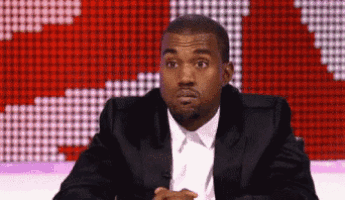 a man in a suit and tie is sitting in front of a screen .