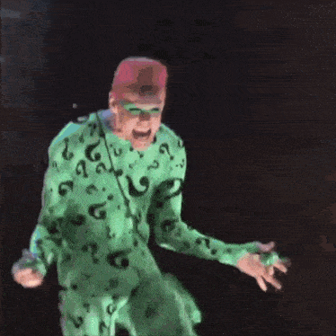 a man in a green riddler costume is standing on a metal surface