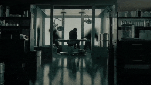 a silhouette of a man in an operating room with a surgical light on