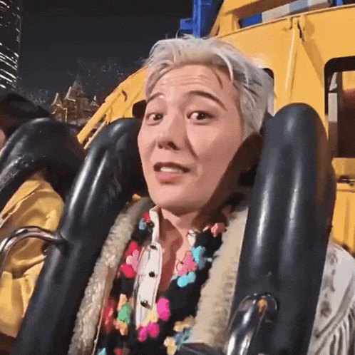 a man is riding a roller coaster with a floral scarf around his neck