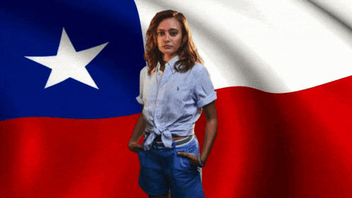 a woman standing in front of a texas flag with her hands in her pockets