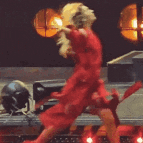 a woman in a red dress is dancing on a stage in front of a crowd .