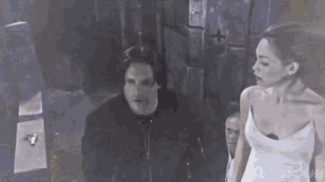 a man and woman are standing next to each other in a dark room .
