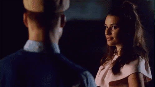 a man and woman are looking at each other in a dark room .