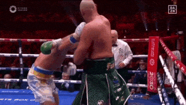 two boxers are fighting in a boxing ring while a referee looks on .