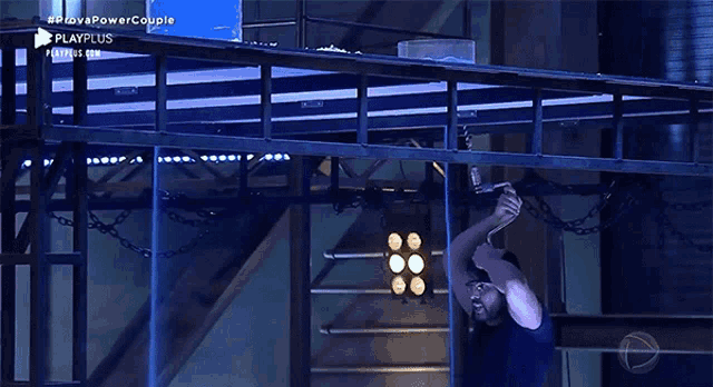 a man is hanging from a rope in a dark room with playplus written on the bottom right