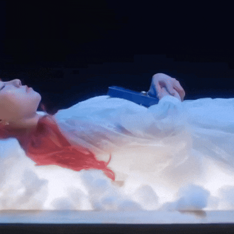 a woman with red hair is laying in a white bed