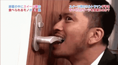 a man in a suit is biting a door handle with foreign writing on it
