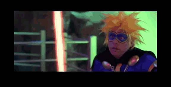 a person with yellow hair and goggles is standing in front of a neon light