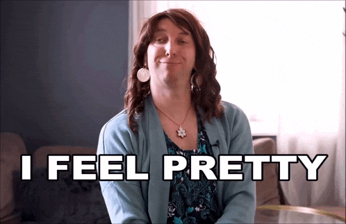 a woman in a blue sweater is smiling with the words i feel pretty behind her