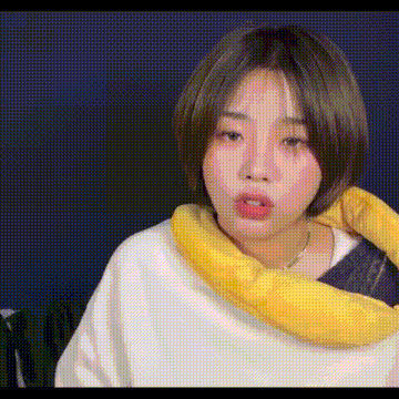 a woman wearing a white sweater and a yellow scarf around her neck is making a funny face .