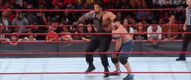 two men are wrestling in a wrestling ring while a referee watches .