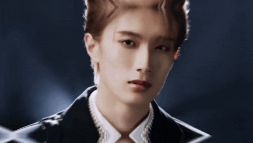 a close up of a young man wearing a black jacket and pearls