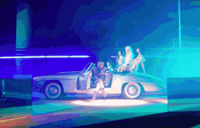 a group of women are sitting in a silver car