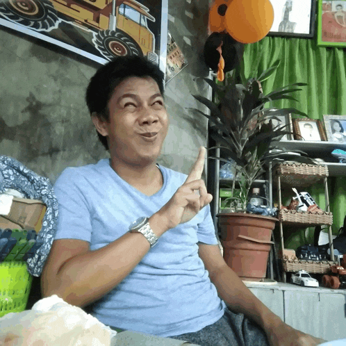 a man in a blue shirt is making a funny face with his finger