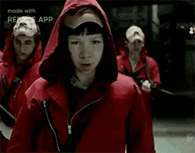 a man wearing a red hoodie and a mask with a mustache is standing in front of a group of people .