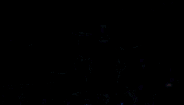 a person playing drums in a dark room with a cross in the background
