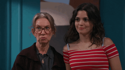two women standing next to each other one wearing glasses and the other wearing a red and white striped top