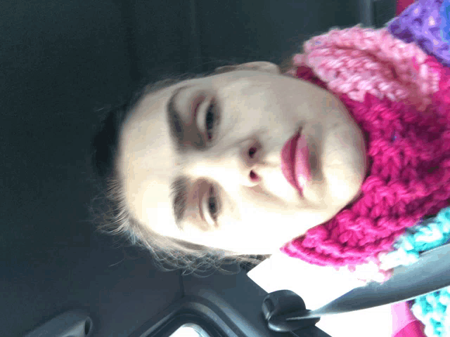 a woman wearing a pink scarf looks down at something