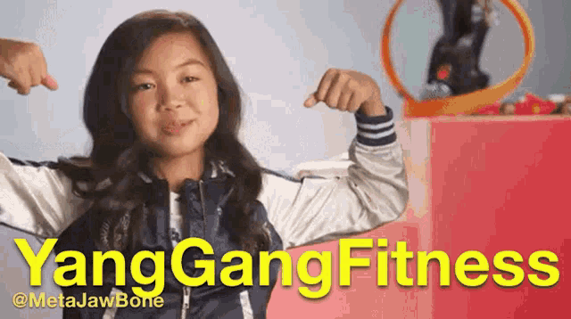 a young girl flexes her muscles in front of a sign that says yang gang fitness