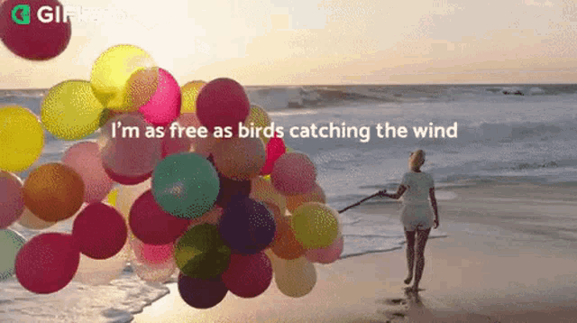a woman holding a bunch of balloons on a beach with the words i 'm as free as birds