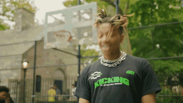 a man wearing a black kicking t-shirt stands in front of a basketball court