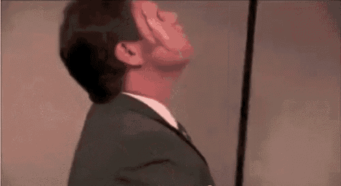 a man in a suit and tie is standing in front of a mirror with his face visible .
