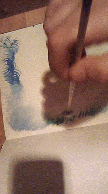 a person is using a brush to paint a picture