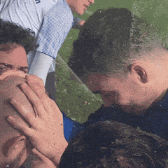 a man covering his face with his hand while another man stands behind him