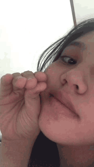 a close up of a woman 's face with a hand on her chin