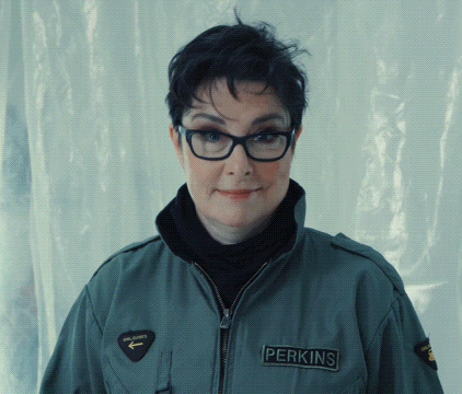 a woman wearing glasses and a jacket that says perkins on it