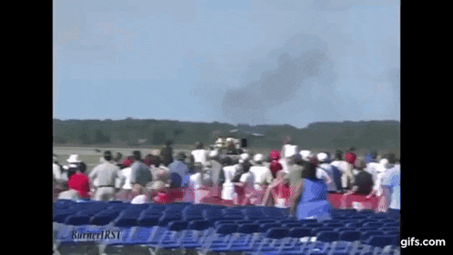 a crowd of people watching a plane take off from a runway ..