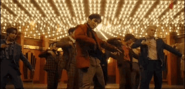 a group of men in suits are dancing in a room with a lot of lights .