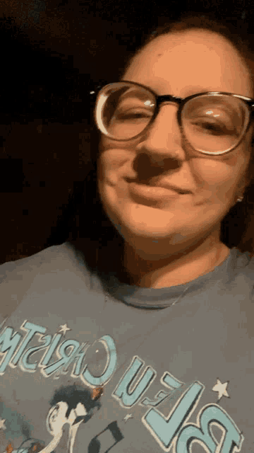 a woman wearing glasses and a blue t-shirt that says ' a ' on it