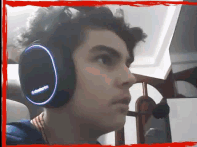a man wearing a pair of steelseries headphones looks at the camera
