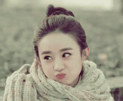 a woman wearing a scarf and a bun making a funny face .