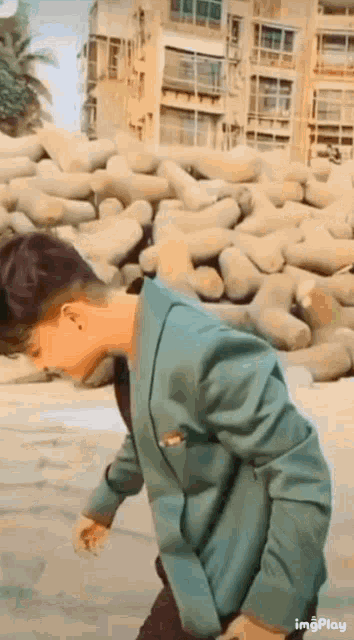 a man in a green jacket is walking in front of a pile of rocks .