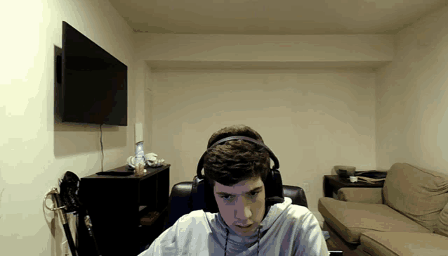 a man wearing headphones sits in front of a television
